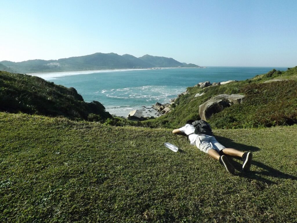 Homem em cima da montanha com vista pro mar